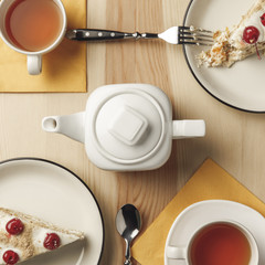 close-up top view of kettle, two cups with hot tea and delicious pastries on table