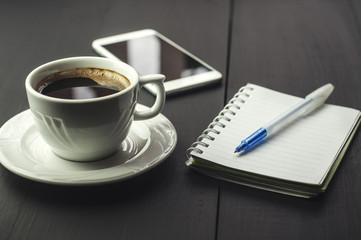 Smartphone with notebook and cup of coffee