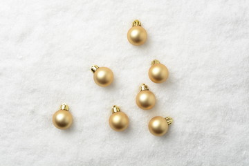 Bolas decorativas de navidad de color dorado en la nieve artificial