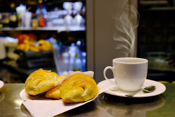 White cup of coffee and croissant over blurred cafe interior