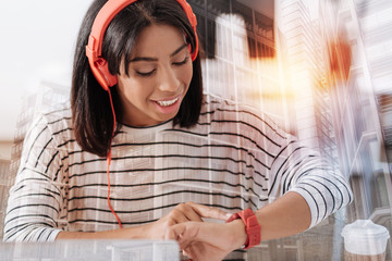 Time checkup. Portrait of smiling woman that bowing head and pointing at her device while having re headphones