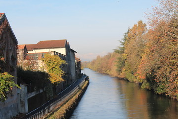 Fototapeta premium Water Canal (channel) and reflections of trees and buildings in Robbecoo sul Naviglio, Italy