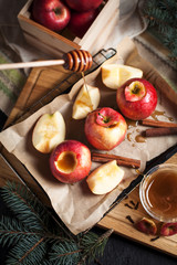 cooking of baked apples for New Year's holidays, Christmas tree and New Year's lights, honey and cinnamon on a wooden cutting board on a dark background