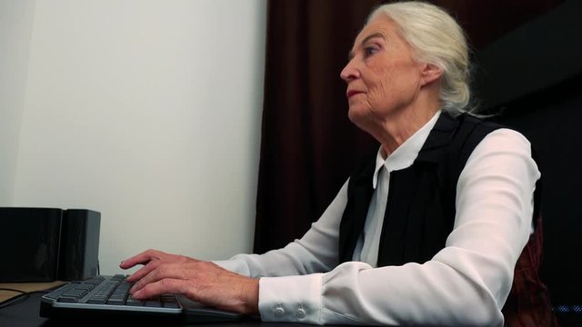 Old caucasian woman works on computer in home 