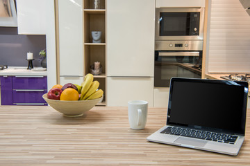cozy modern kitchen interior with laptop and fruits in bowl