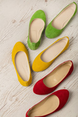 Colorful shoes (ballerinas) on a white wooden background.