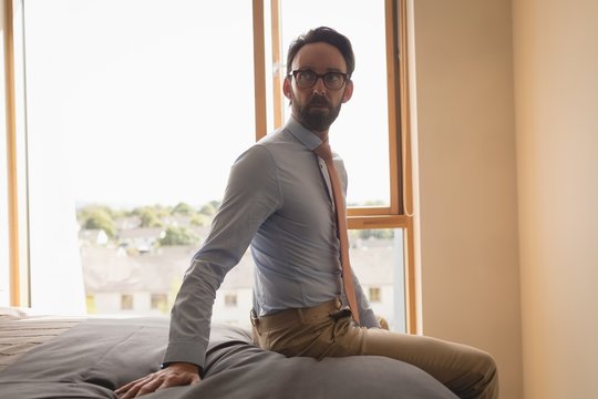 Man sitting on bed in bedroom