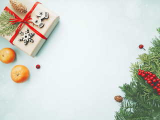 Christmas background. Christmas present or gift box with decorations, fir tree branches and mandarins on light background. Flat lay and top view composition with copy space design.