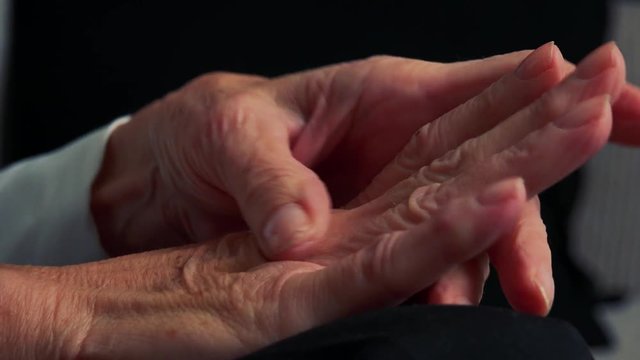 Closeup hands of old caucasian woman - she sits in living room 