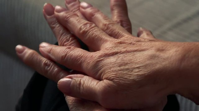 Closeup hands of old caucasian woman - she sits in living room 