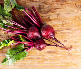 свежий урожай красной свеклы с ботвой на деревянной поверхности стола 