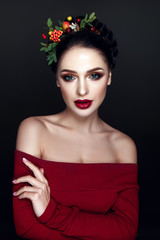 Beautiful woman portrait with red and yellow berries on head and with black hair and red lips.