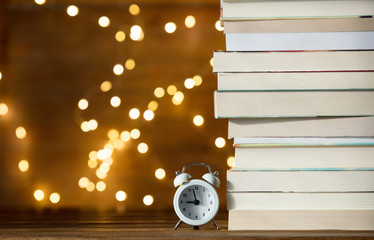 Vintage alarm clock and pile of books and fairy lights