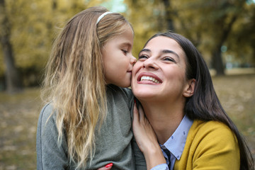 Fototapeta premium Mother and daughter in nature have fun. Daughter kissing her mom.