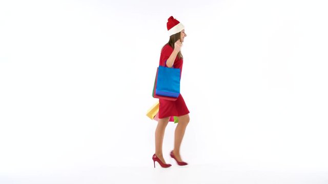 Christmas female shopper holding multicolored shopping bags on white background in studio. Let's go holiday shopping concept