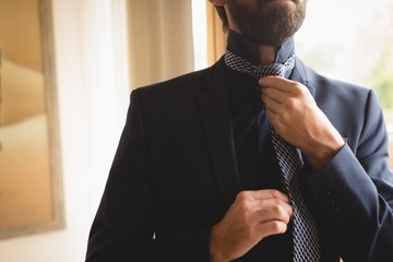 Man wearing his tie at home