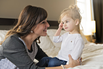 Mother and her daughter child girl taking good time on bed