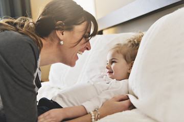 Mother and her daughter child girl taking good time on bed
