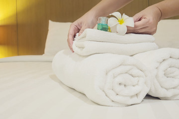 Lady set up white towel set on bed in hotel room