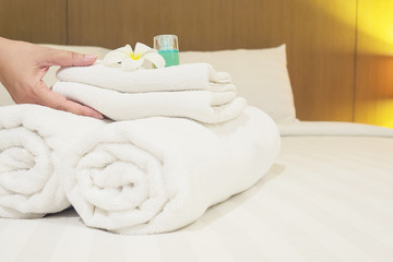 Lady set up white towel set on bed in hotel room