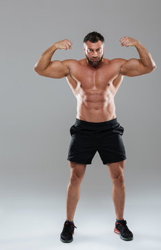 Full length portrait of a muscular concentrated shirtless male bodybuilder