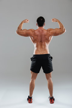 Back view full length portrait of a strong male bodybuilder
