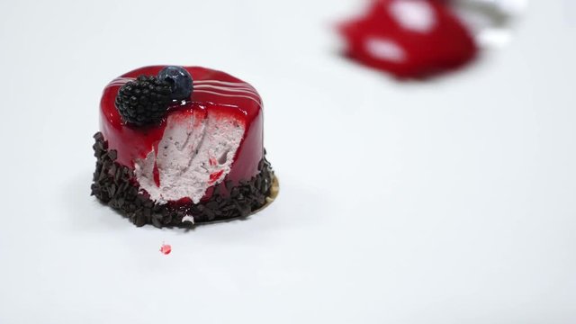 A person starts to eat a red mono portion cake...