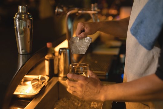 Waiter putting ice cubes into glass