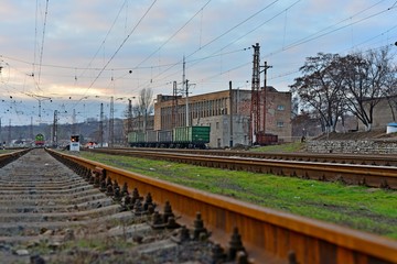 Obraz premium Railway station against beautiful sky at sunset. Industrial landscape with railroad, colorful cloudy blue sky. Railway sleepers. Railway junction. Heavy industry. Cargo shipping. Travel background