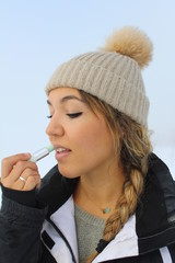 Fototapeta premium GIRL APPLYING LIP BALM AT SNOW