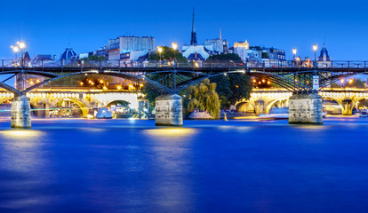 Naklejka premium Love Bridge called Pont des Arts on a famous beautiful La Seine river in Paris, France. Best tourists destination in Europe. Taken by long exposure by night photography. Landmark in Paris and historic