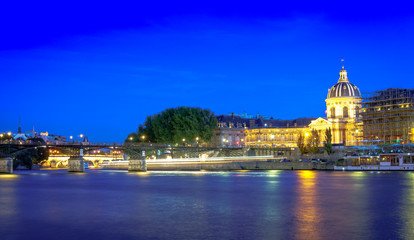 Fototapeta na wymiar Love Bridge called Pont des Arts on a famous beautiful La Seine river in Paris, France. Best tourists destination in Europe. Taken by long exposure by night photography. Landmark in Paris and historic