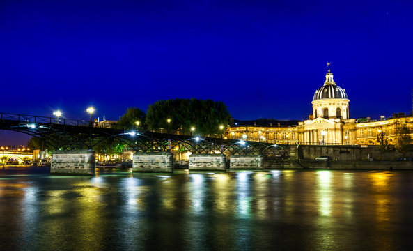 Love Bridge called Pont des Arts on a famous beautiful La Seine river in Paris, France. Best tourists destination in Europe. Taken by long exposure by night photography. Landmark in Paris and historic