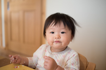 A baby that is dirty by grabbing rice and eating it by hand / A Japanese baby of 11 months of age