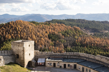 Fototapeta na wymiar The courtyard of a medieval castle with tower on the background of forest and mountains