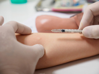 A physician holds a syringe needle above a diabetic patient's arm after an insulin injection. Healthcare and metabolic syndrome concept.