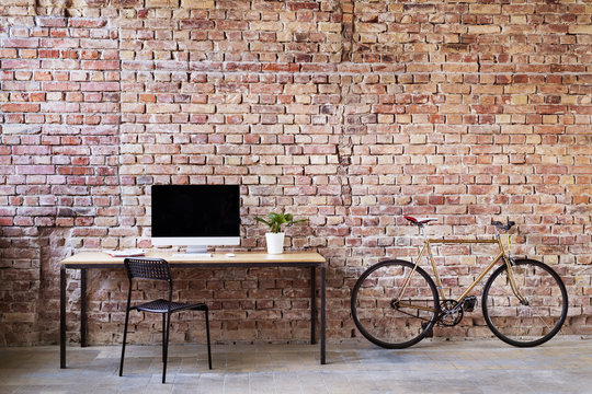 Workspace and bicycle at brick wall in office