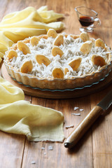 Vegan Coconut Banana Tart on round wooden board, on wooden table