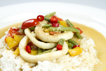 Squid rings in chilli curry sauce with green beans, tomatoes, peppers. Served with rice. Thai food.