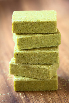 Vegetable bouillon, stock or broth cubes on wooden plate, photographed with natural light (Selective Focus, Focus on the front upper edges of the top cubes)