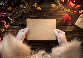 Close up of Santa Claus hands holding, reading blank letter with copy space