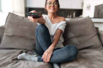 Happy young woman sitting on sofa at home watch TV.