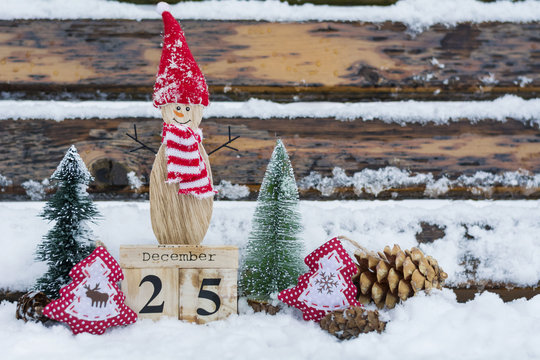 Christmas Pine Tree ,Snowman and Wooden Calendar with Date on Snowy Wooden Background. Christmas Concept