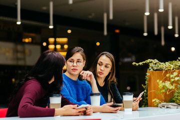 Group of three beautiful young woman using smartphone in cafe, modern lifestyle with gadget technology or working woman on freelance business concept.
