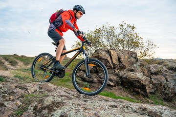 Fototapeta na wymiar Cyclist in Red Riding the Mountain Bike down Autumn Rocky Trail. Extreme Sport and Enduro Biking Concept.