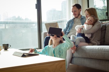 Parents using laptop while girl using digital tablet