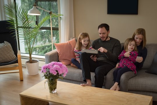 Family using digital tablet and mobile phone in living room