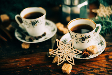 Two cups of espresso with pieces of cane sugar and Italian coffee maker on wooden table.