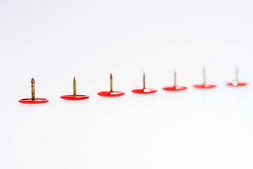Row of red thumbtacks isolated on white background