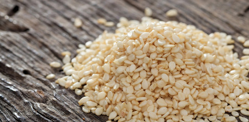 A heap of raw sesame seeds, on wooden surface. Closeup view.